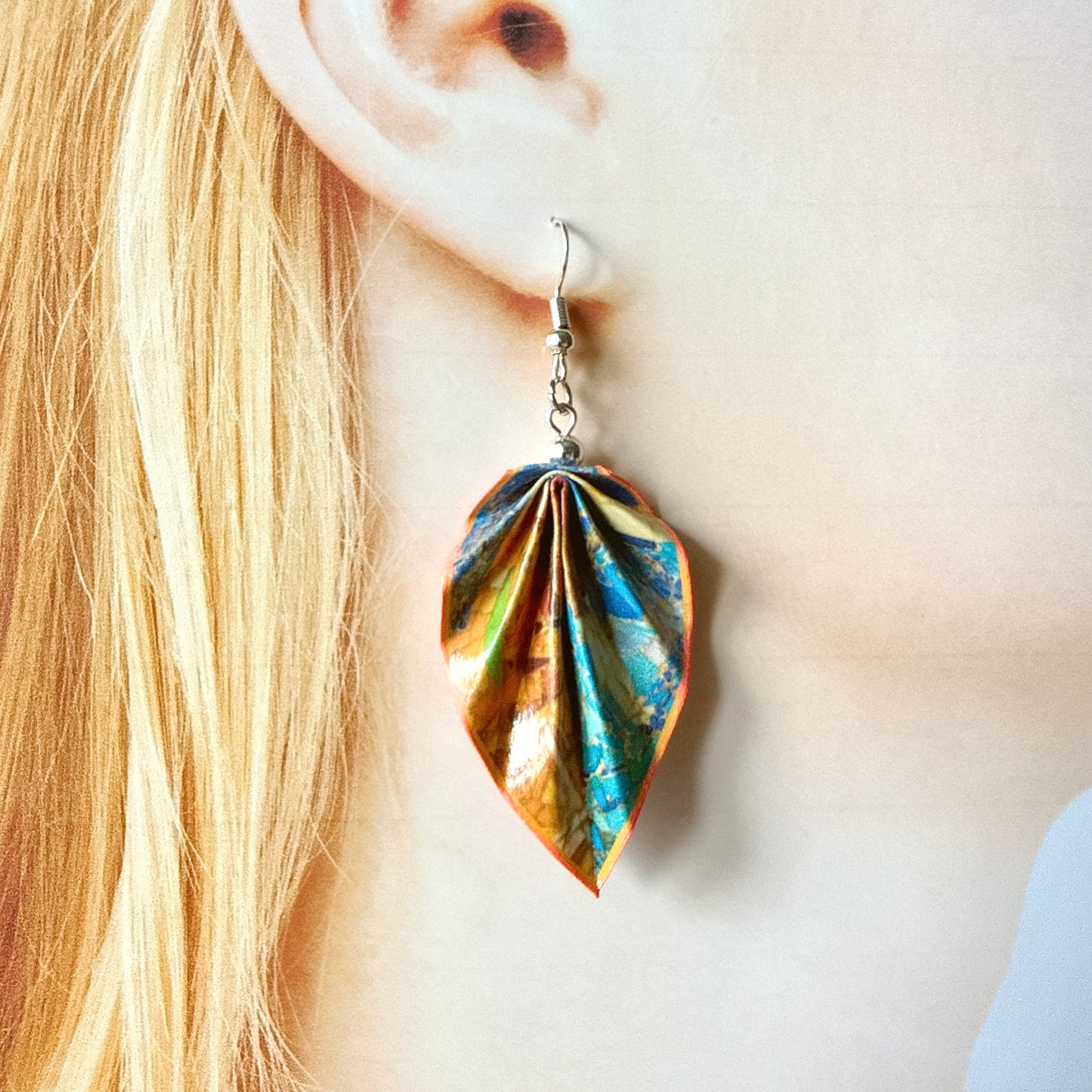 Leaf-shaped earrings worn by a person with blonde hair.