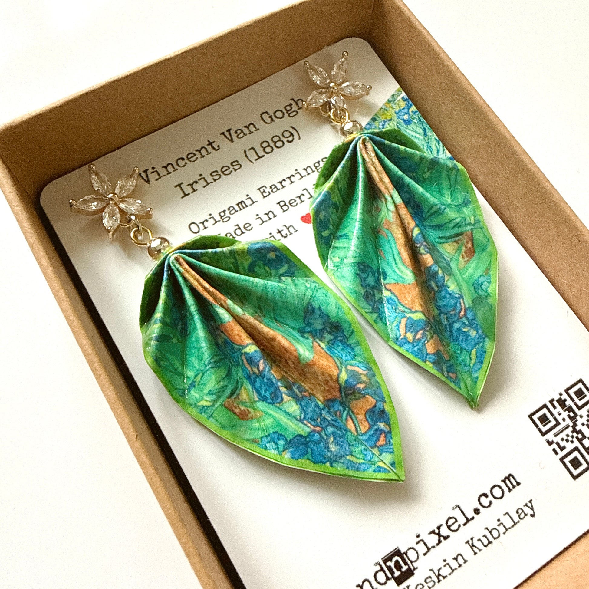Pair of origami-style earrings with floral design on a branded box