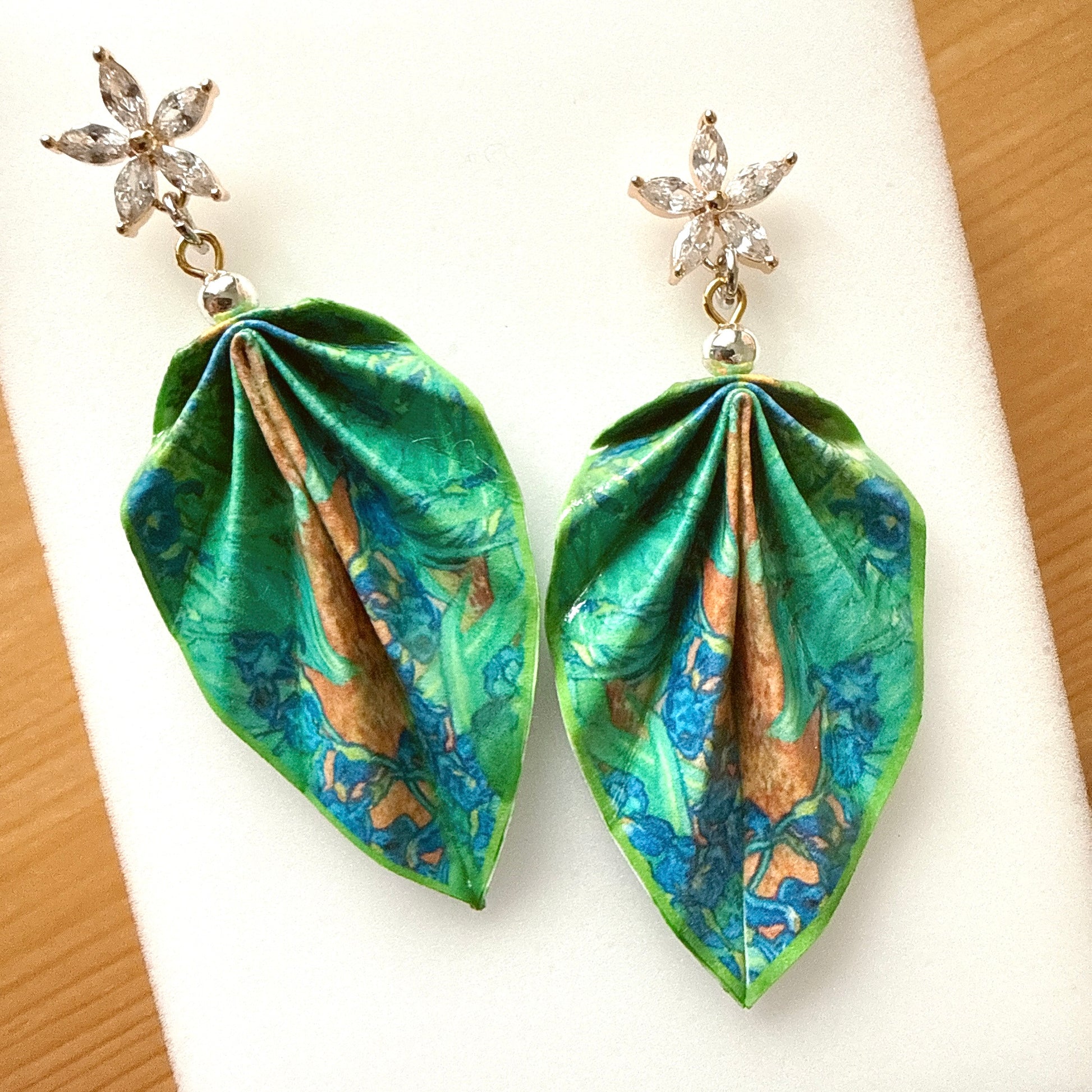 Pair of earrings with green and blue floral patterns on a white background