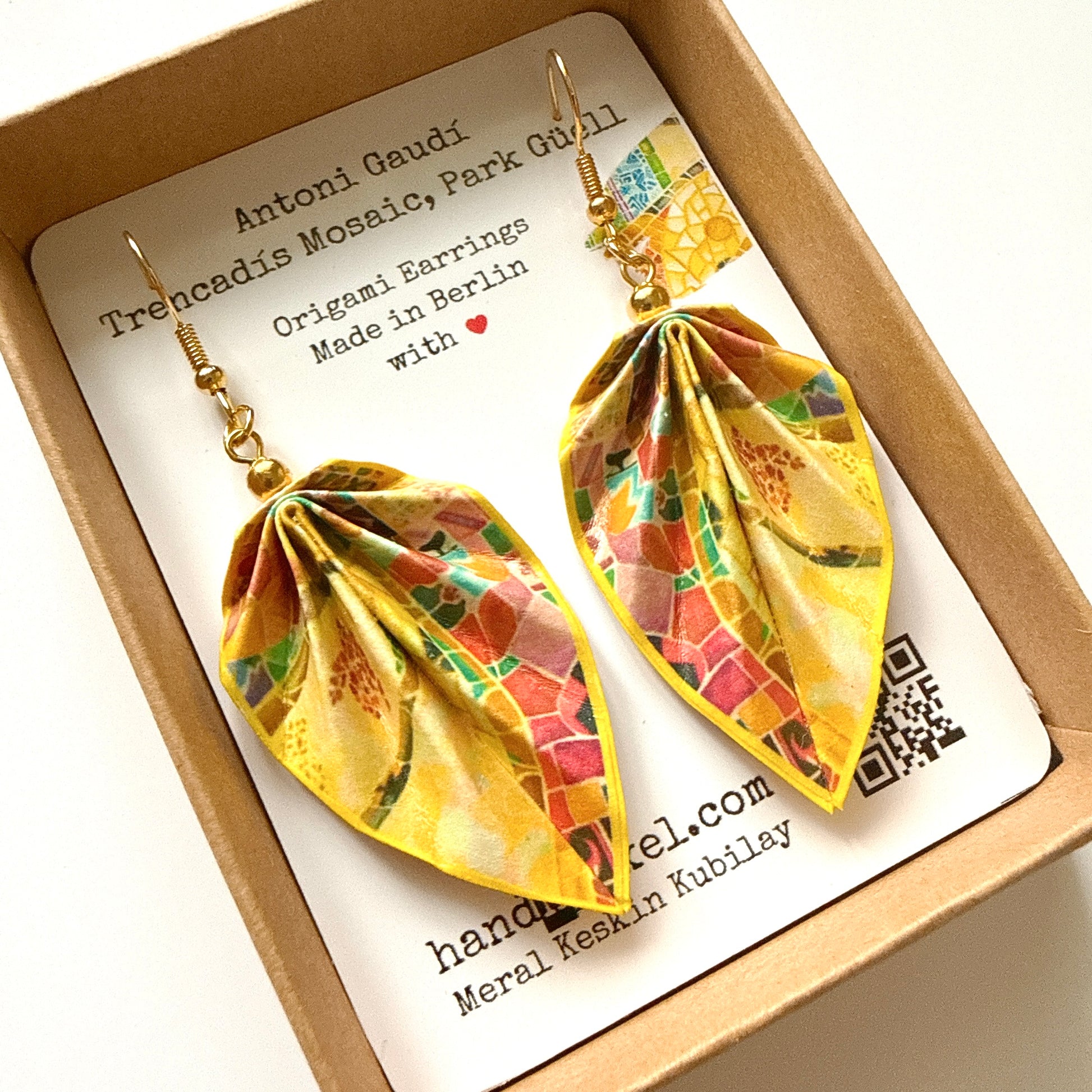 Colorful origami earrings on a branded card with 'Antoni Gaudi' text.