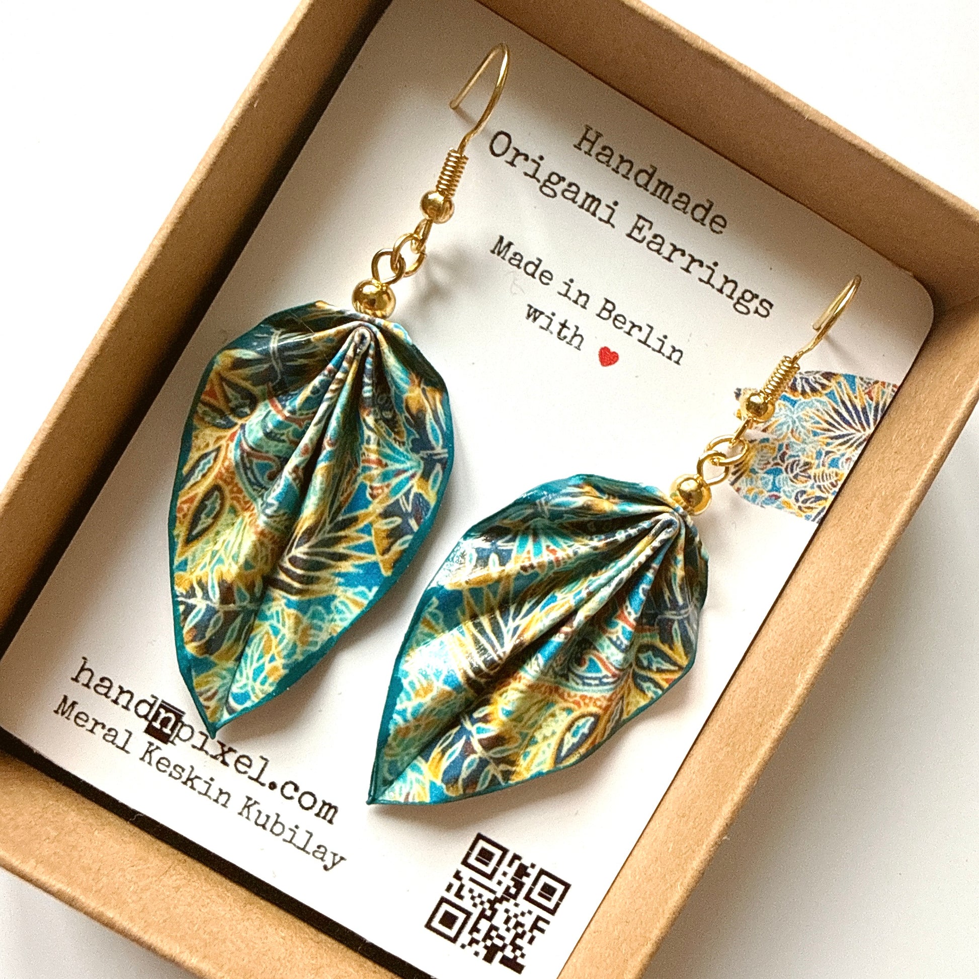 Handmade origami earrings in a box with a brand card.