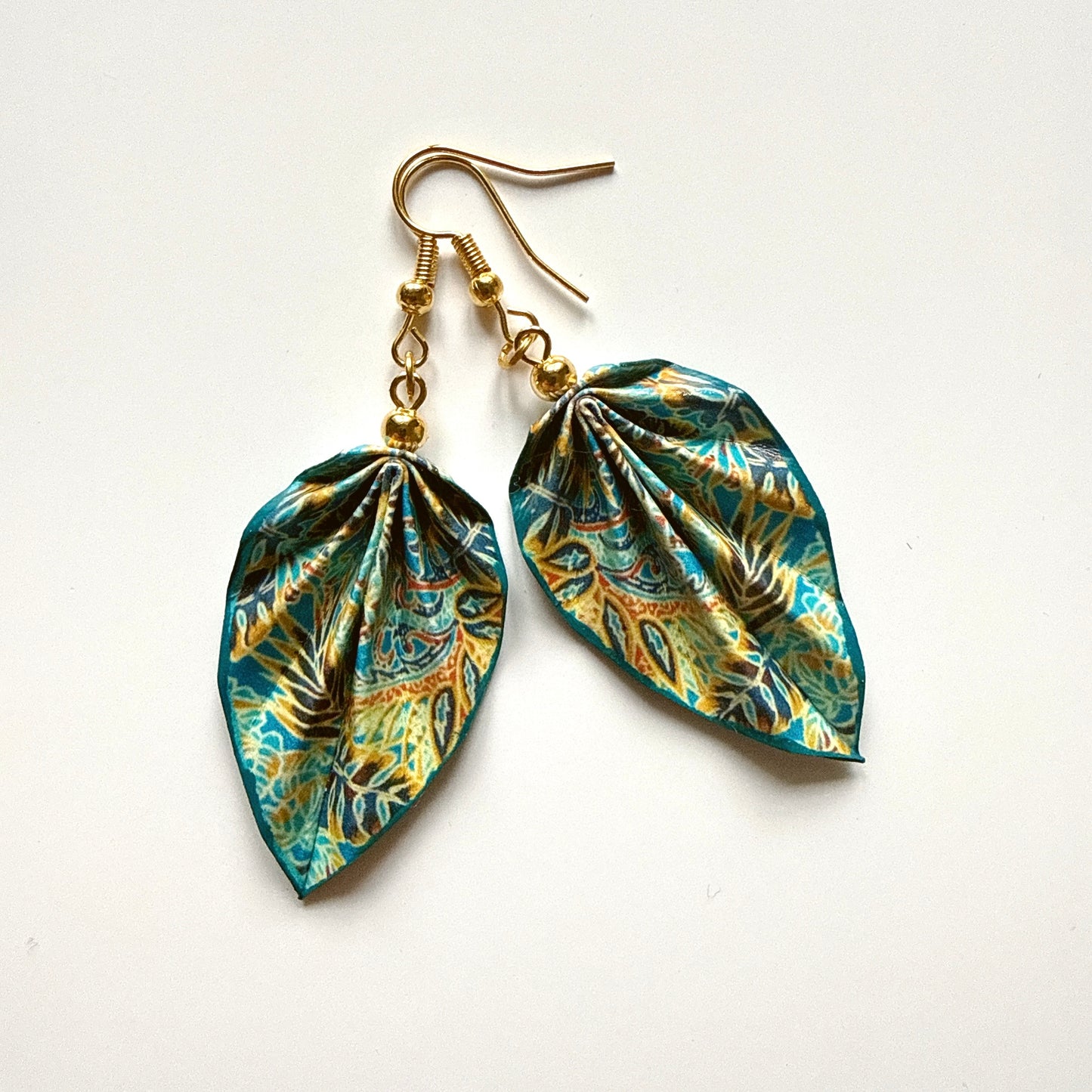 Pair of leaf-shaped earrings with gold hooks on a white background