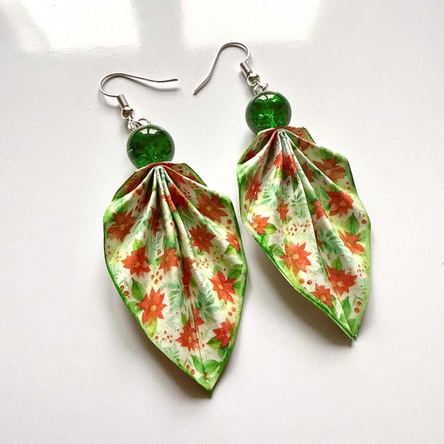 Pair of leaf-shaped earrings with floral pattern on a white background