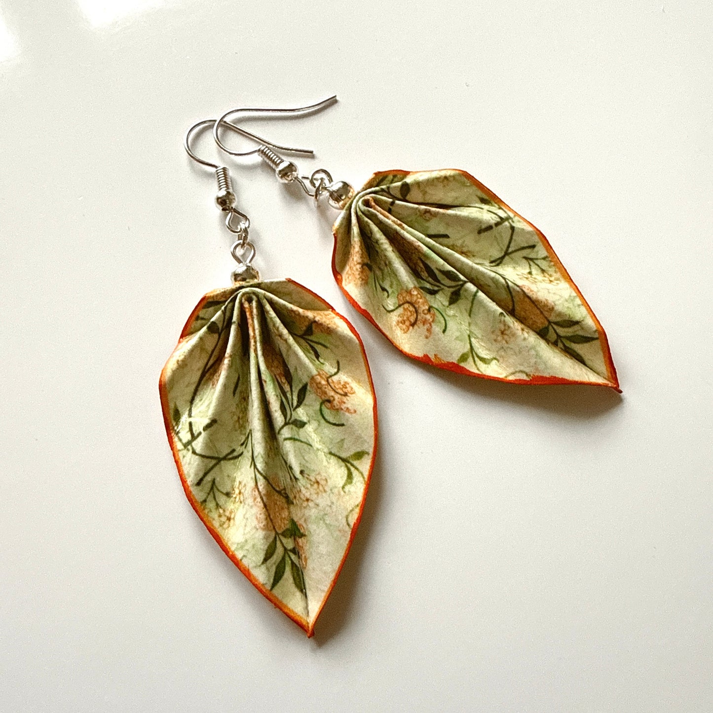Leaf-shaped earrings with floral patterns on a white background